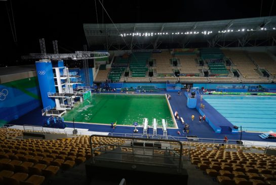 The water of the diving pool at left appears a murky green in stark contrast to the pool's previous day's color and also that of the clear blue water in the second pool for water polo at the venue as divers train in the Maria Lenk Aquatic Center at the 2