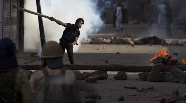 A protester throws a plank of wood at policemen during a protest in Srinagar on Tuesday