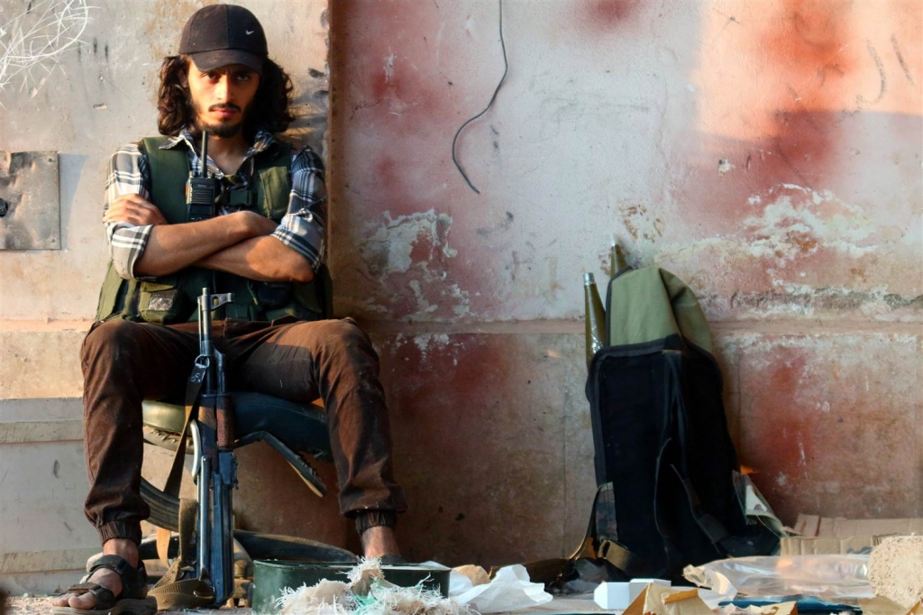 Image A rebel fighter sits with his weapon in the artillery academy of Aleppo