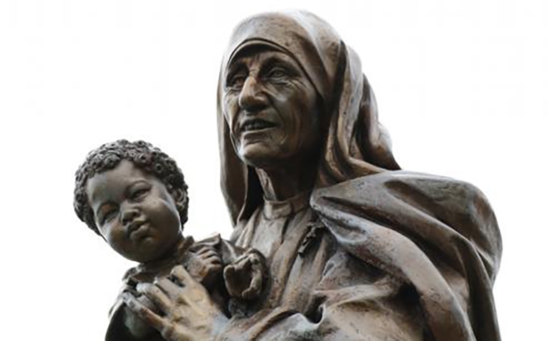 A statue of Blessed Teresa of Kolkata holding a child is seen in a prayer garden at Cure of Ars Church in Merrick N.Y