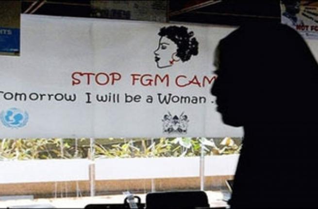 A woman walks past a poster from a campaign to stop FGM in Egypt