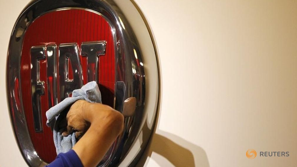 A worker polishes a Fiat logo during the launch of Chrysler's flagship showroom in Los Angeles