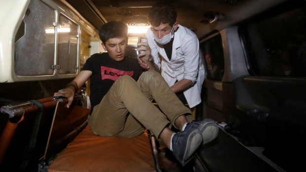 A wounded man is helped by a medic inside an ambulance following the attack at the American University of Afghanistan in Kabul