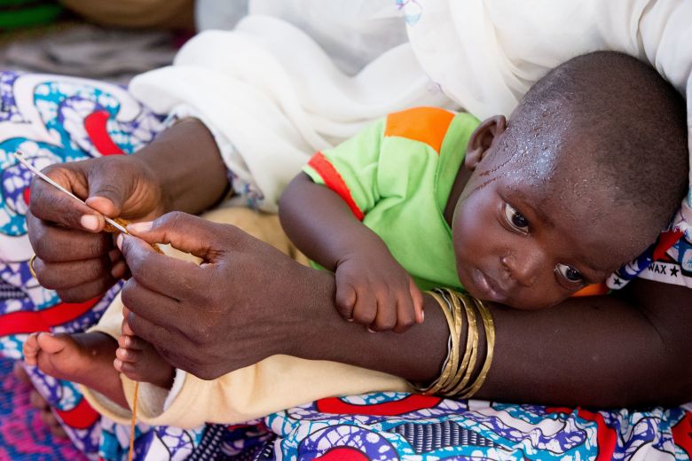 A young child lays in the arms of a displaced woman at the Malkohi Internally Displaced Person Camp in Yola Nigeria