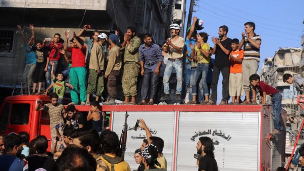 A group of men and boys gather on a vehicle in celebration