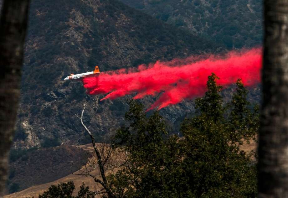 A plane aids in firefighting efforts behind Hearst Castle as a wildfire burns in San Simeon Calif. Saturday Aug. 20 2016. A growing wildfire in central California has forced the closure of the historic Hearst Castle. Fire officials say the blaze was