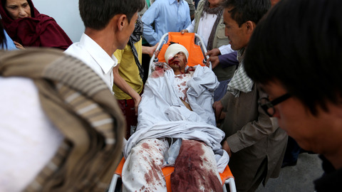 Afghans help a man who was injured in a deadly explosion that struck a protest march by ethnic Hazaras in Kabul