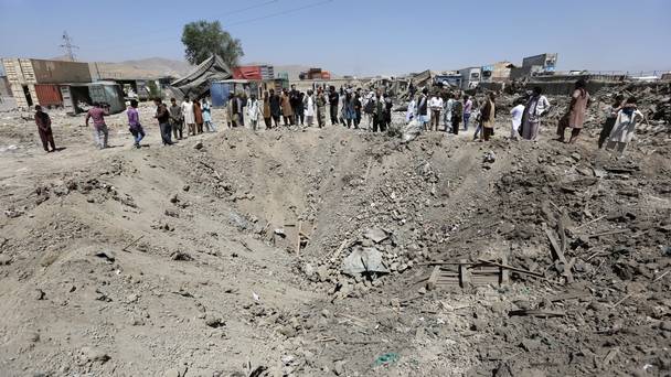 Afghans look at a crater caused by a truck bombing in Kabul