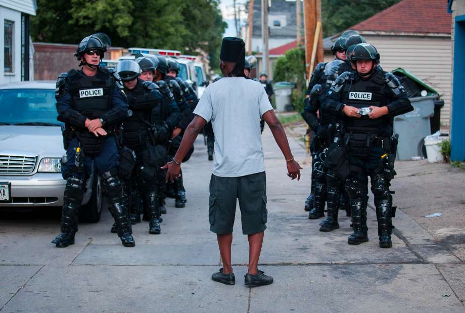 A man talks to police Monday in the Milwaukee neighborhood where violence broke out after an officer killed a black man