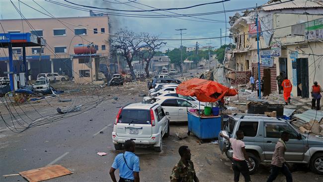 People and security forces walk across the scene of a car bomb attack claimed by al Shabab militants in Mogadishu Somalia