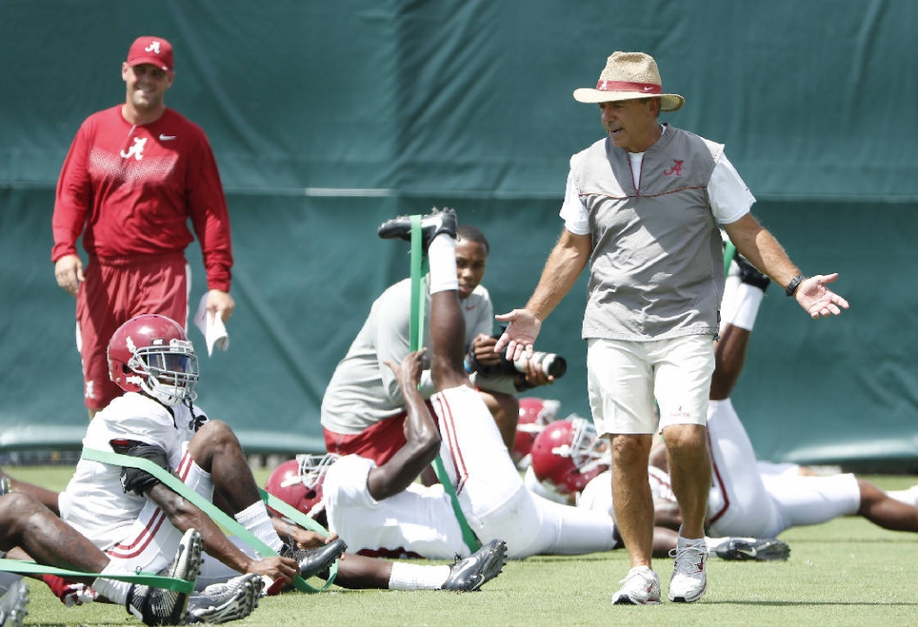 Alabama football coach Nick Saban speaks to players as they stretch before Tuesday's practice in Tuscaloosa