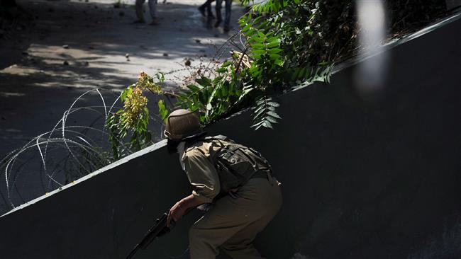 An Indian policeman prepares to fire a pellet gun towards Kashmiri protestors during clashes in Srinagar