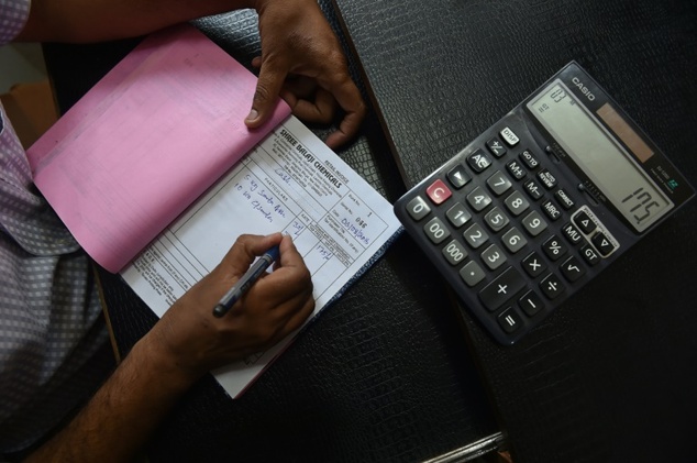 An Indian shopkeeper prepares a bill for a customer at his shop in New Delhi