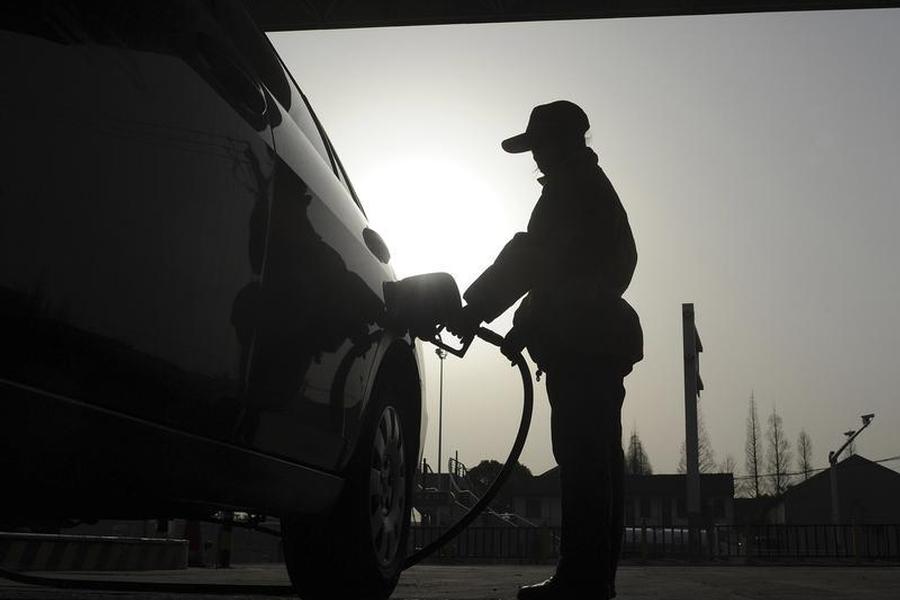 An employee fills a car tank at a petrol station in Hefei Anhui province