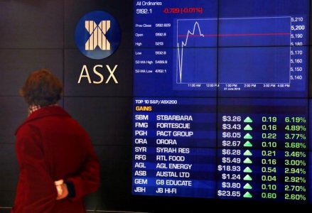 An investor walks past a board displaying stock prices at the Australian Securities Exchange in Sydney Australia