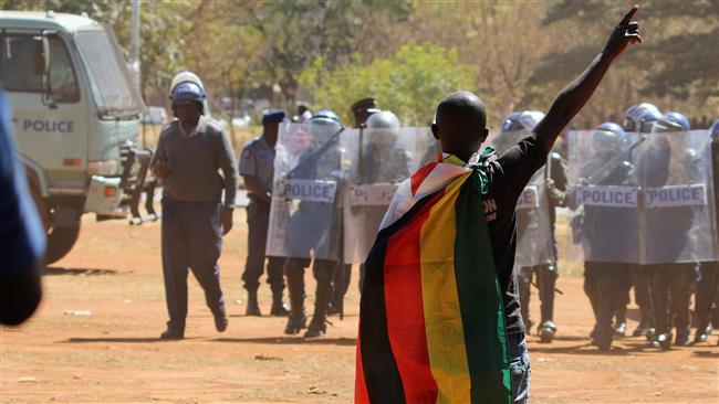 An opposition supporter faces police officers during a protest in Harare Zimbabwe