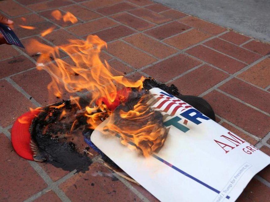 Anti-Trump demonstrators burn Donald Trump's campaign items outside a campaign event in San Diego California US