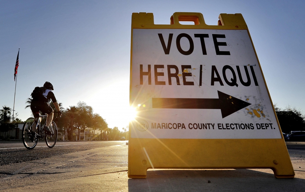 A cyclist rides past a sign directing voters to a primary election voting station early Tuesday Aug. 30 2016 in Phoenix