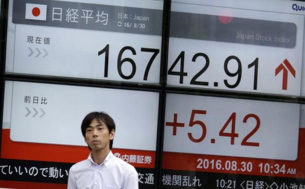 A man walks past an electronic stock board