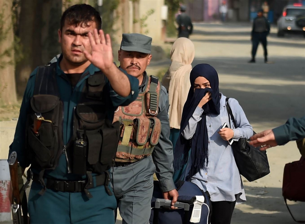 Image A student who had been trapped inside the American University of Afghanistan during the attack is escorted out by police