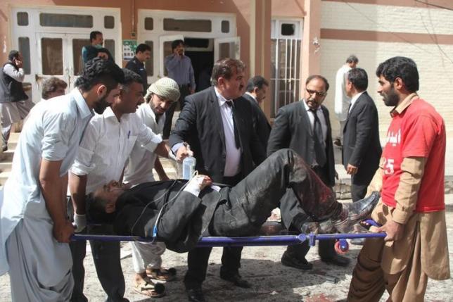 First responders and volunteers transport an injured man away from the scene of a bomb blast outside a hospital in Quetta Pakistan