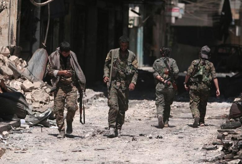 Syria Democratic Forces fighters walk on the rubble of damaged shops and buildings in the city of Manbij in Aleppo Governorate Syria