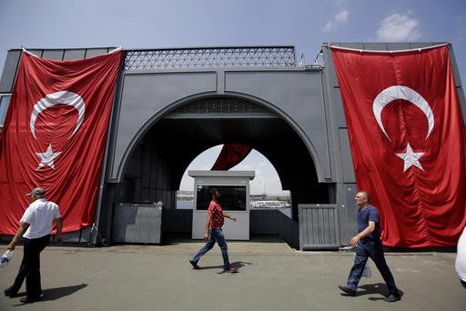 Men walk at the Galata bridge past two Turkey flags in Istanbul on Tuesday Aug. 2 2016. Turkey's justice minister has sent a document to the United States seeking the arrest of cleric Fethullah Gulen who lives in self-imposed exile in Pennsylvania