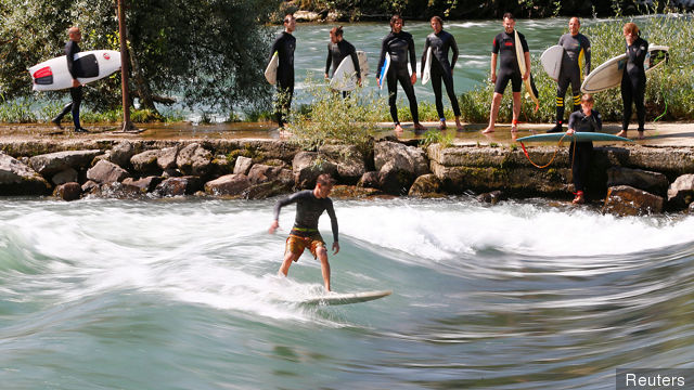 A man surfs on a wave on the Reuss river during sunny weather in the town of Bremgarten