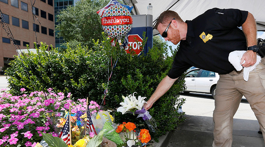 A Louisiana law enforcement officer places flowers on a makeshift memorial at Our Lady of the Lake Regional Medical Center in Baton Rouge Louisiana U.S