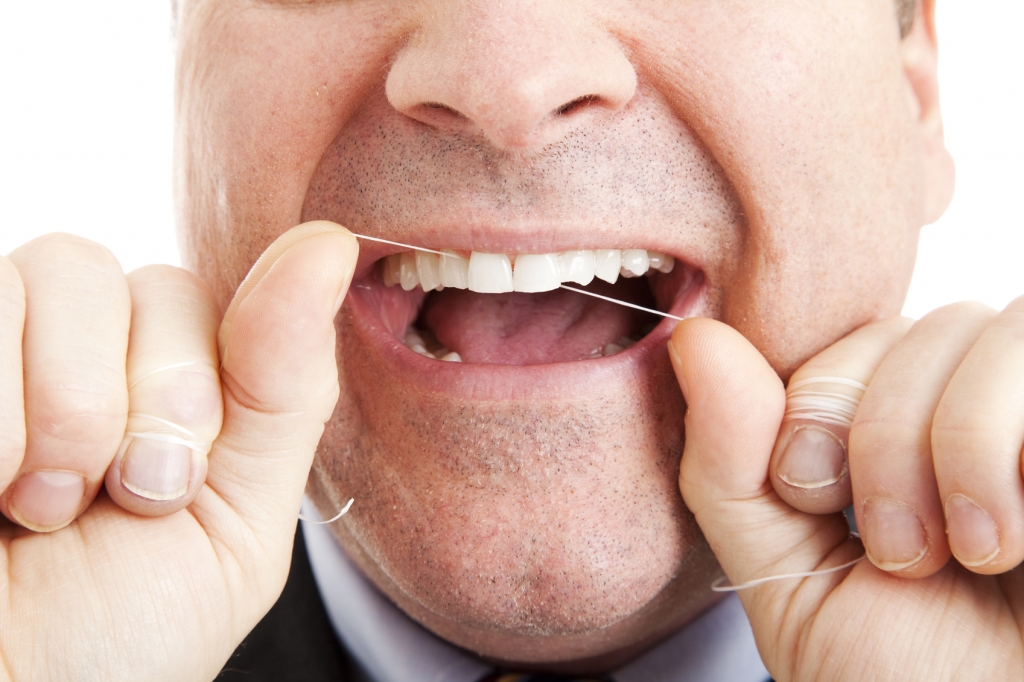 Closeup of a man flossing his teeth with dental floss