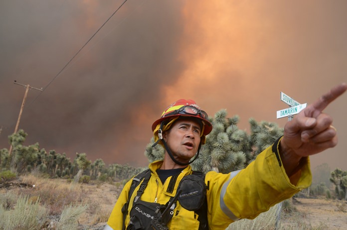 A San Bernardino County Fire captain looks for a better place for his crew while fighting the Bluecut Fire Wednesday Aug. 17 in Cajon Pass Calif