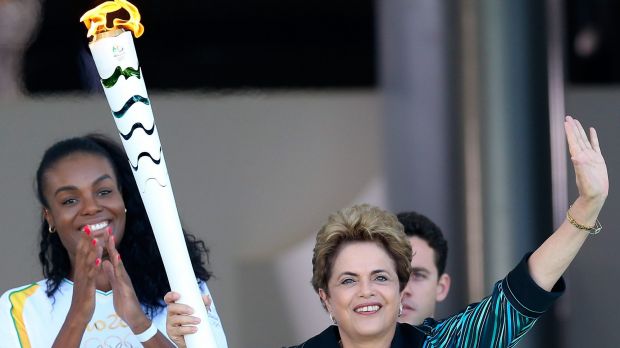 Suspended Brazilian President Dilma Rousseff hands the Olympic torch to the first torch bearer Brazilian volleyball