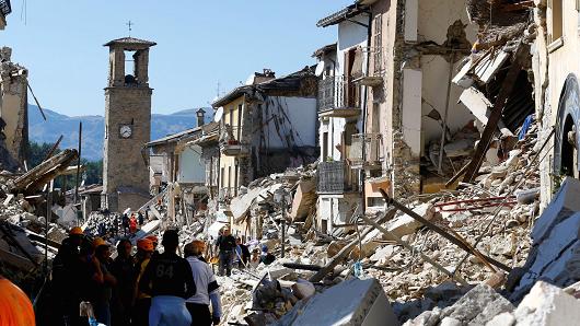 People stand next collapsed buildings following an earthquake in Amatrice Italy