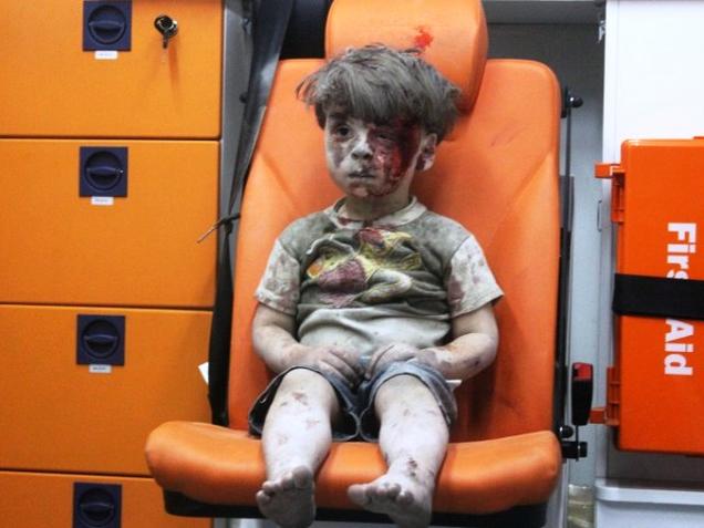 Omran a Syrian boy covered in dust and blood sits in an ambulance after being rescued from the rubble of a building hit by an air strike in the rebel-held Qaterji neighbourhood of the northern Syrian city of Aleppo