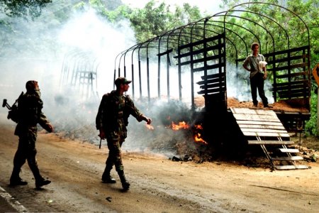 Two colombian soldiers patrol in front at a truck burned by rebels of the Revolutionary Armed Forces of Colombia in Cisneros 80 kms west from Cali Valle del Cauca province