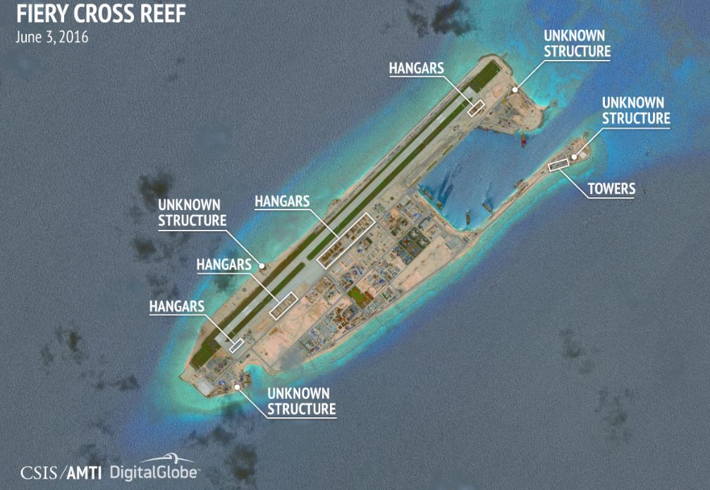 A satellite image of Fiery Cross reef shows the landing strip sprinkled with hangars