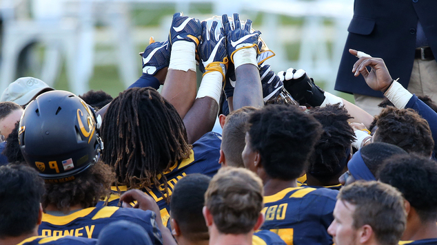 California Golden Bears players reach up to touch the trophy presented to them ofter defeating the Hawaii Rainbow Warriors at the end the opening game of the