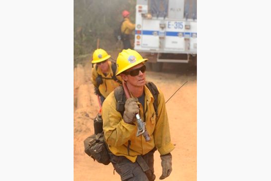 Santa Barbara County firefighters haul hose up a hillside while working to hold a wildfire from crossing a fire break on the India Division near Cachagua in east Carmel Valley calif. on Wednesday Aug. 3 2016. As officials ask for the public's help