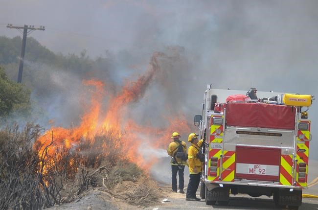 Mike Callaway of the San Bernardino County Fire Department attacks burning brush along Highway 173 while battling a wildfire in Hesperia Calif. Monday Aug. 8 2016