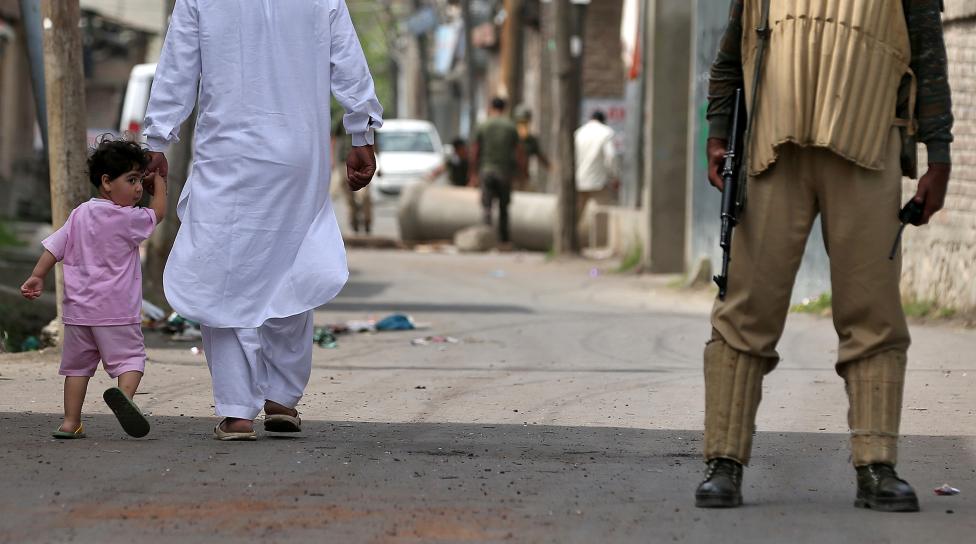 A boy looks back at a member of the security forces in Srinagar as the city remains under curfew following weeks of violence in Kashmir