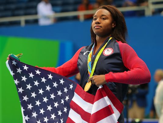 Simone Manuel with an American flag after the women's 100m freestyle final in the Rio 2016 Summer Olympic Games at Olympic Aquatics Stadium