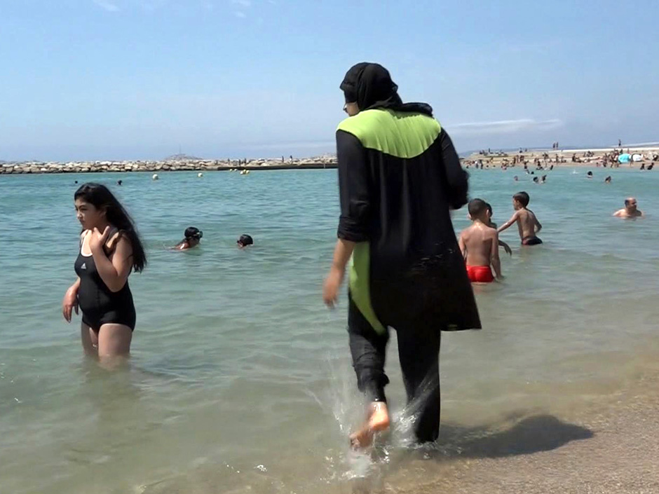 A woman gets into the sea wearing traditional Islamic dress in Marseille southern France. The French resort of Cannes has banned full-body head-covering swimsuits worn by some Muslim women from its beaches citing security concerns