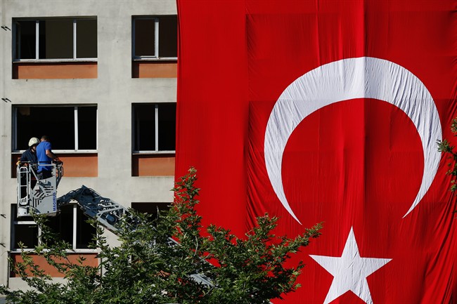 Workers drape a huge Turkish flag on a facade of a building damaged in Tuesday's explosion in Istanbul Wednesday