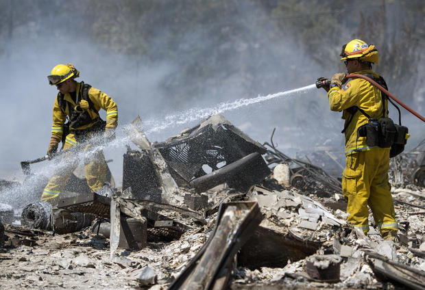 Carlos Orta right of Santa Cruz Calfire douses the smoldering remains of a home in Lower Lake Calif. Monday Aug. 15 2016.               JOSH EDELSON AP