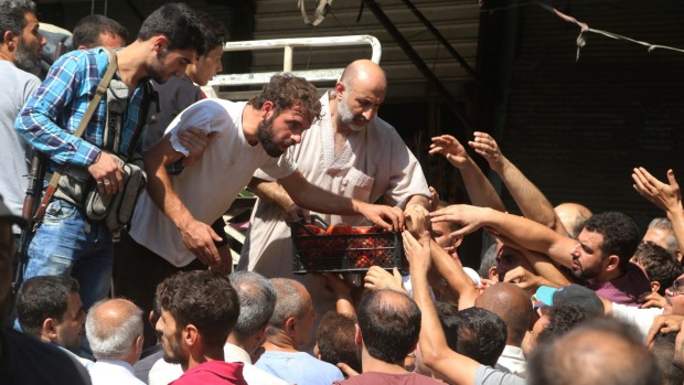 People gather to buy fresh produce that was brought into rebel held areas of Aleppo by private traders from a newly