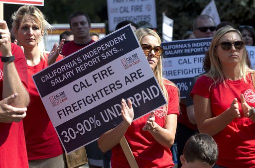 Laura Sutton center the wife of California Department of Forestry and Fire Protection firefighter Nick Sutton joins others at a rally calling for shorter hours and higher wages to retain firefighters at the Capitol Monday Aug. 22 2016 in Sacrament