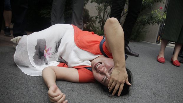 Fan Lili the wife of imprisoned activist Gou Hongguo lies on the ground after being knocked over by plainclothes