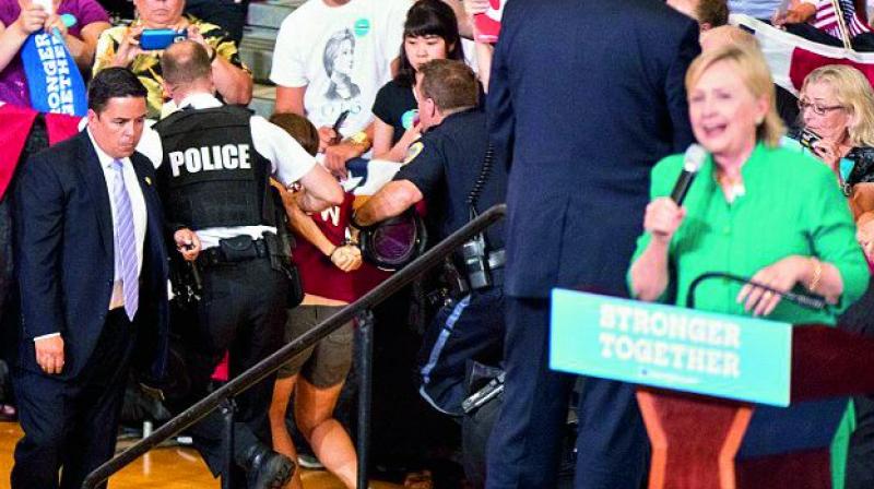 Secret Service agents escort a protester who tried to disrupt a Hillary Clinton rally in Des Moines. The woman an animal rights activist tried to rush onto the stage but struggling was escorted out by security