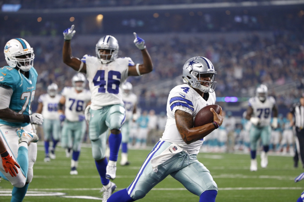 Dallas Cowboys&apos Dak Prescott runs the ball into the end zone for a touchdown as teammate Alfred Morris celebrates in the first half of an NFL preseason football game agains the Miami Dolphins in Arl