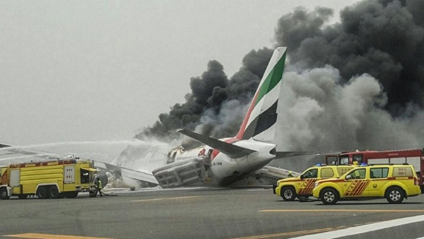 Crews work to extinguish a fire on Emirates flight EK521 after it was involved in an accident